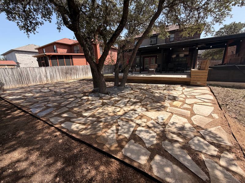 Flagstone patio set in decomposed granite with steel edging around an oak tree, with a new low deck and bench box behind