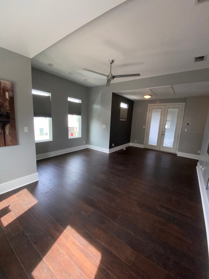 Open living area with dark wood-look plank flooring, grey walls and French doors