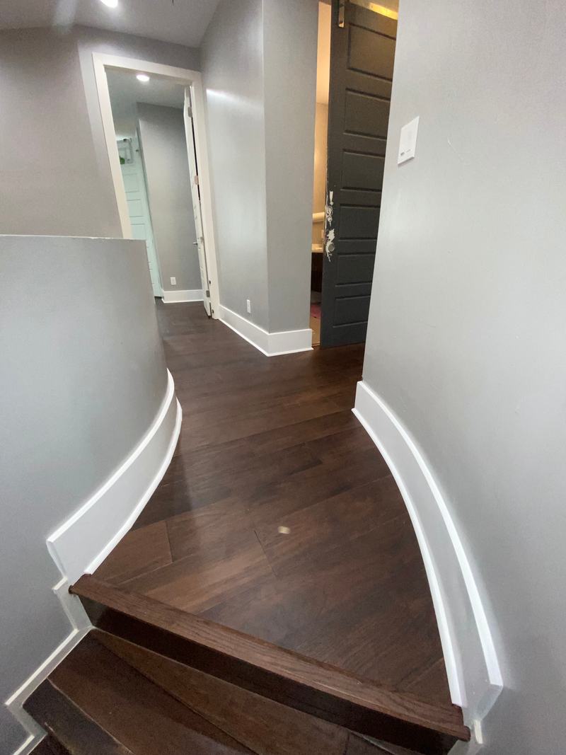 Curved stair landing finished with dark plank flooring and matching stair nosing