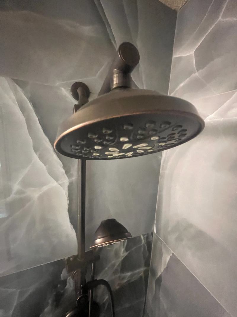 Bronze rain shower head and handheld shower on onyx-look tile