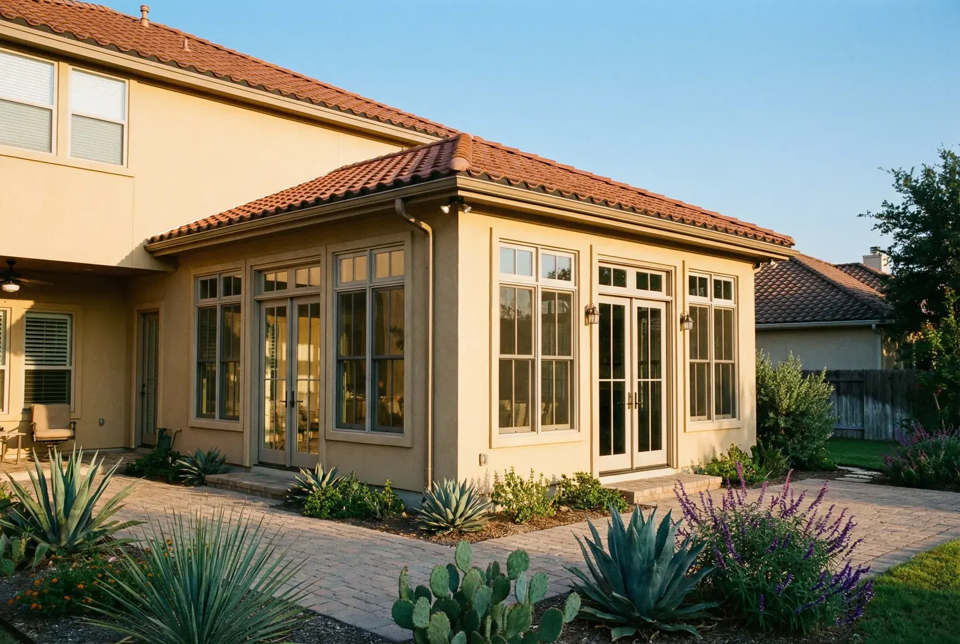 Stucco home addition with tall windows, French doors and a tile roof.