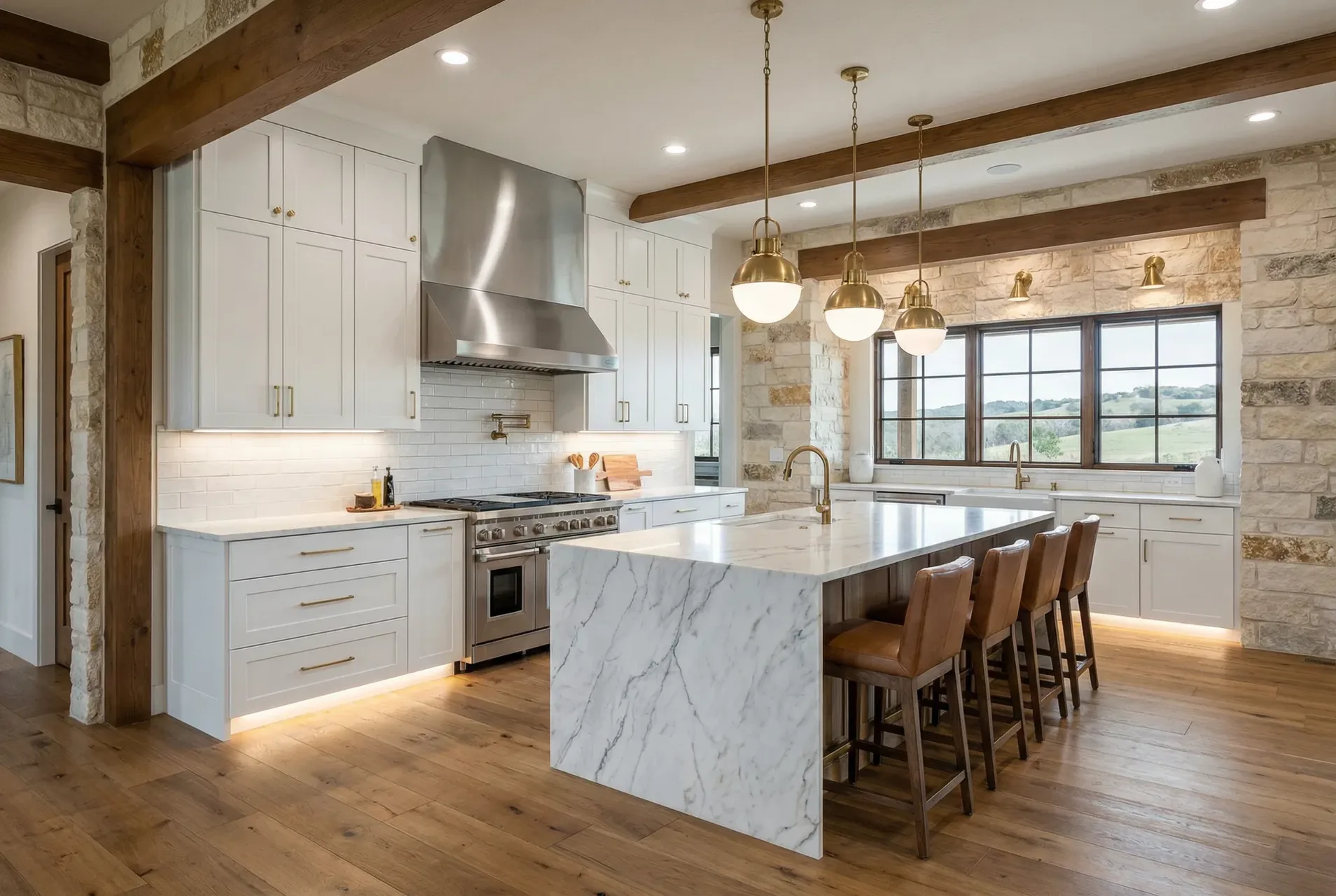 Kitchen with white cabinets, a marble waterfall island, pendant lights and a stainless range hood.
