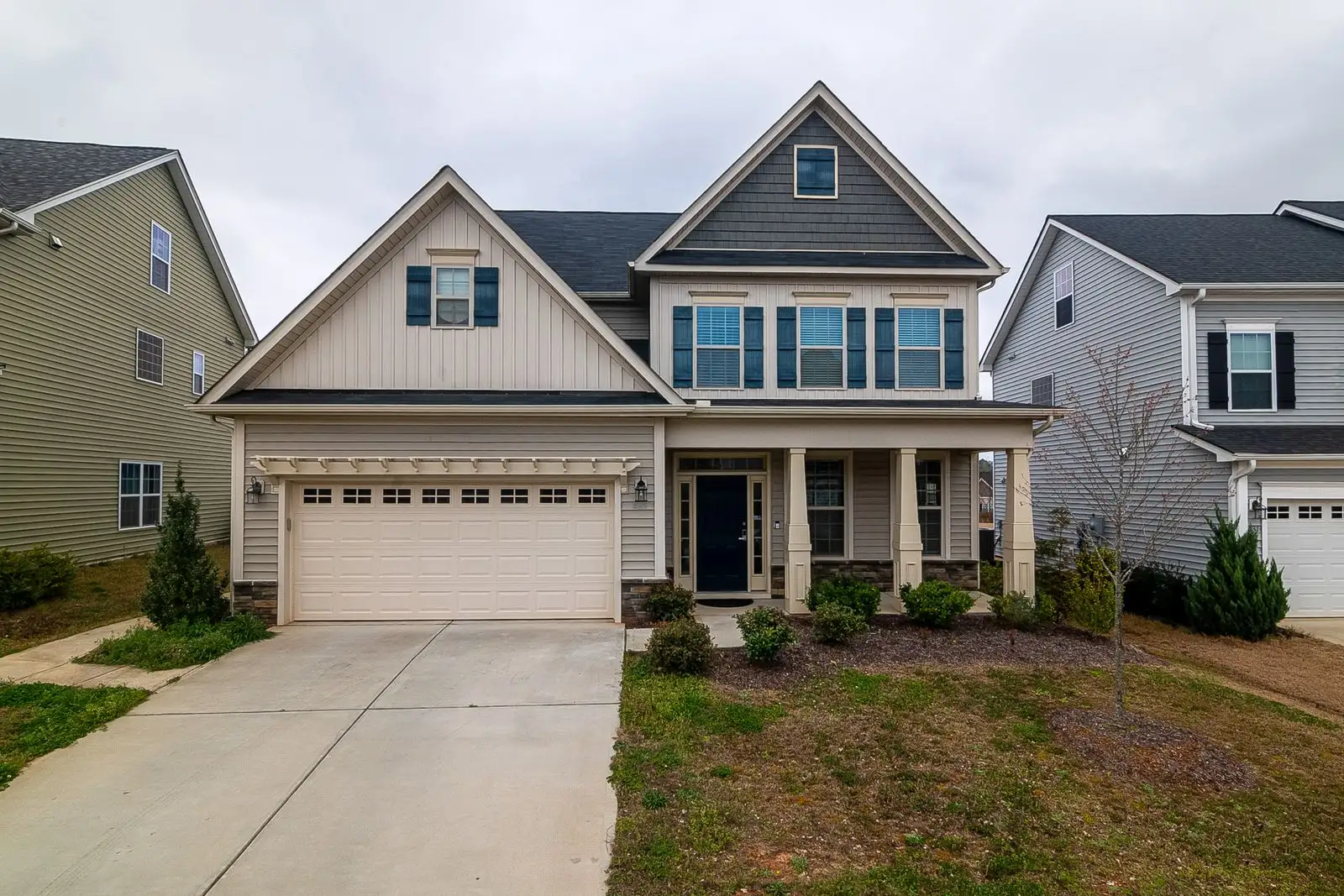 Two-story suburban home with a garage and concrete driveway on a sunny day.