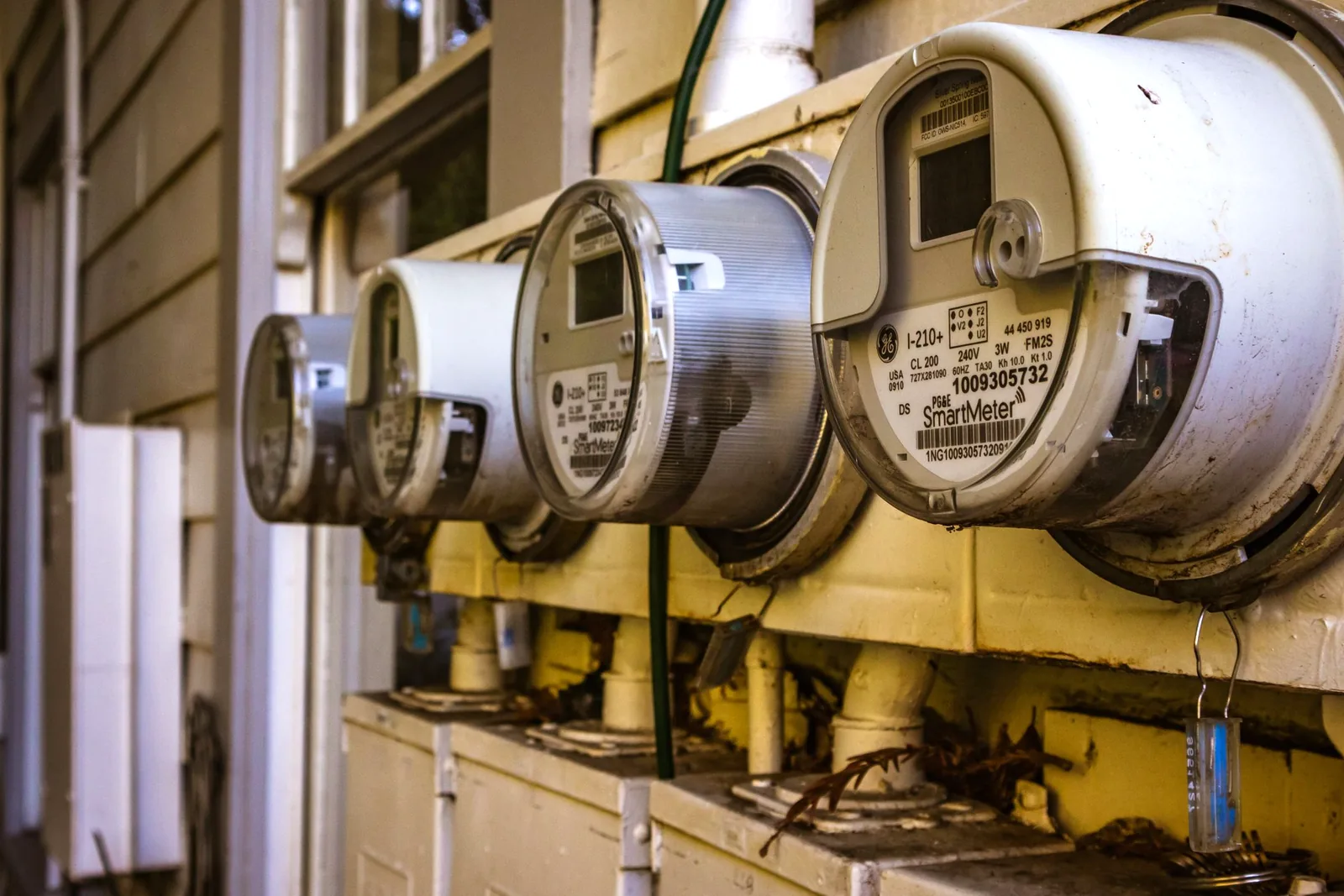 Row of round electric meters mounted on the exterior wall of a residential building.